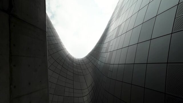 Dark concrete and glossy tiled walls rise into a narrow opening of sky in South Korea, creating a dramatic urban canyon composition.