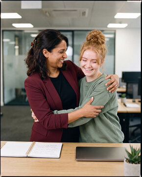 Two women embracing in a modern office