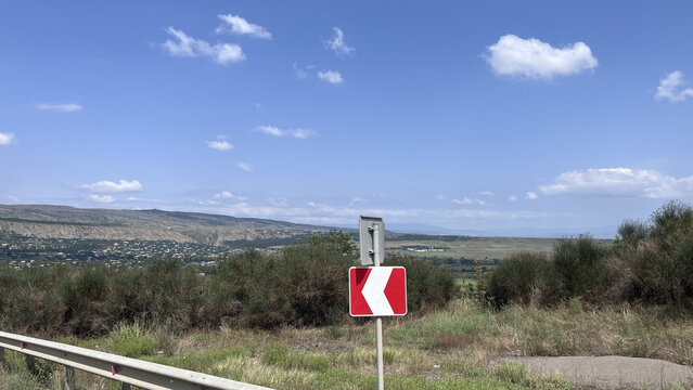 Road curve warning sign on rural hillside