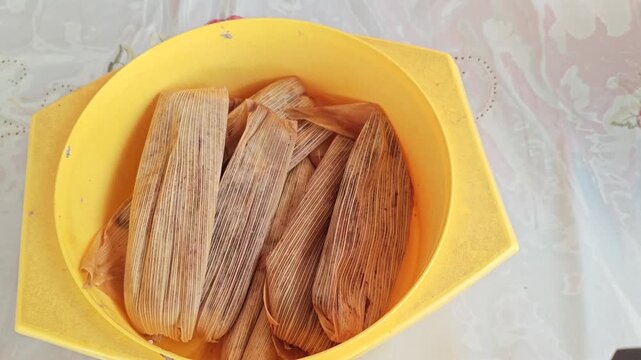 Close Up of Homemade Corn Husk Tamales Arranged on Yellow Tray