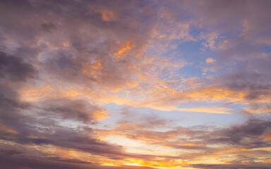 Obraz premium Vibrant Sunset Sky with Fiery Orange and Purple Clouds,A dramatic and colorful sunset sky filled with textured clouds. The setting sun casts intense golden-orange and warm yellow light from.