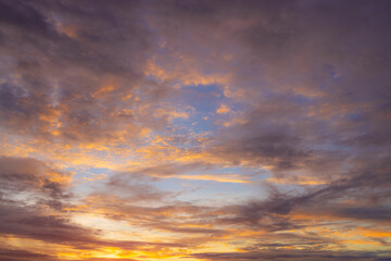 Obraz premium Vibrant Sunset Sky with Fiery Orange and Purple Clouds,A dramatic and colorful sunset sky filled with textured clouds. The setting sun casts intense golden-orange and warm yellow light from.