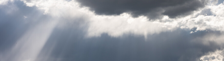 Fototapeta premium Dramatic sky with dark storm clouds building for ominous weather, Crepuscular Rays, God Rays, light shafts beaming down, as a nature background, Yellowstone National Park 