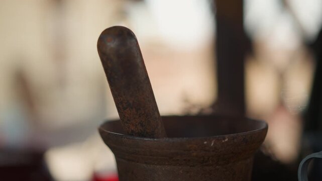 a close-up shot of a wooden mortar and pestle in an indoor kitchen setting, captured with a slightly angled view. The scene features neutral tones and a still atmosphere, emphasizing.