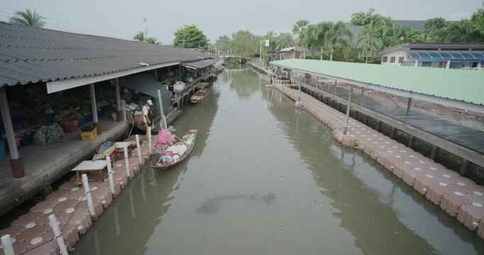 Crowded wooden boats in canal with fruits, vegetables, foods and grocery products for sell and trade by villagers at Tha Kha traditional floating market Samut Sogkhram, Thailand