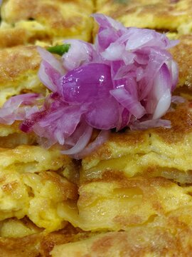 golden-brown egg omelet or egg roll (telur dadar) served on a black rectangular plate.