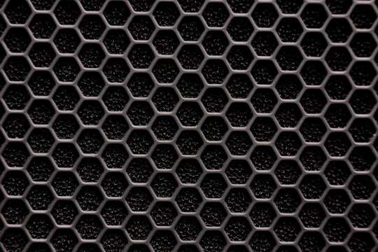 Extreme close-up macro photograph of a black industrial honeycomb mesh grille.