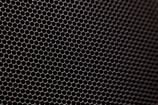 The composition features a dense, repeating pattern of uniform circular holes arranged in a precise hexagonal grid.