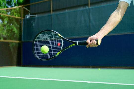 Tennis Player Hitting Ball with Racket on Blue and Green Hard Court Close Up Action Shot