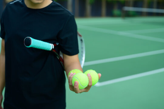 Tennis Player Holding Three Yellow Balls and Racket on Green Court Ready to Serve