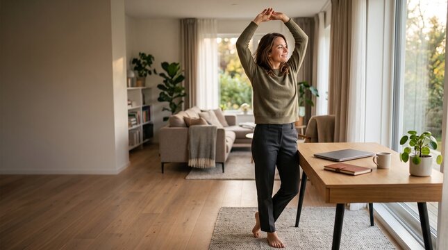 Woman stretching during a work break in her modern bright home office