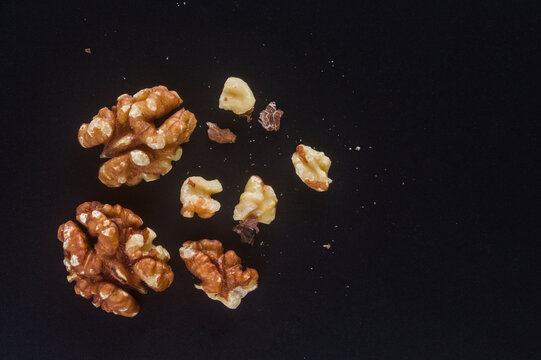 Walnut kernel halves on a black background with copy space