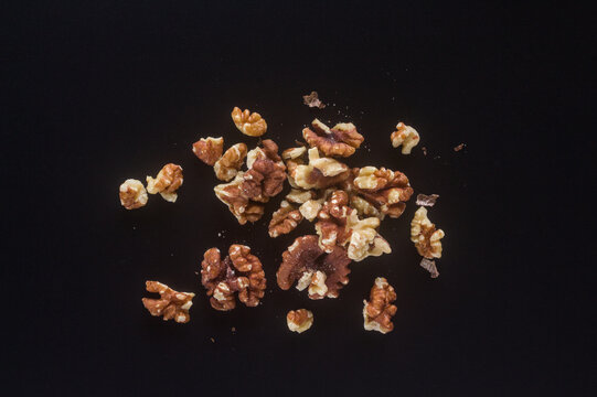 Walnut kernels scattered on a black background