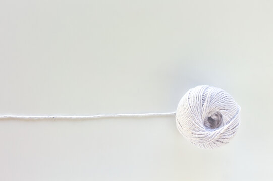 White yarn ball with a straight thread line on a white background