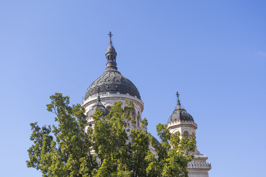 Historic cathedral domes rising above green trees against clear blue sky