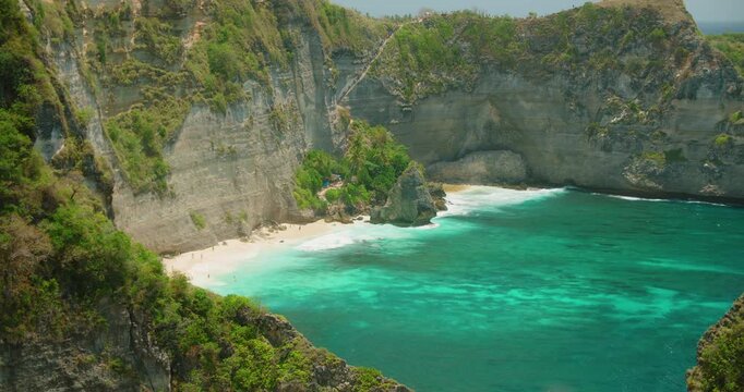 Remote tropical beach surrounded by tall cliffs and crystal clear ocean at Diamond Beach Nusa Penida Island Bali