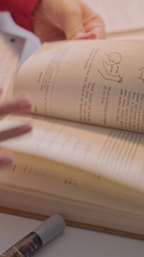 Close up of young woman. Her hands interact with printed material revealing diagrams like bridges charts labeled DEATH on y axis 1905 1926 x axis. Pen is held between her fingers