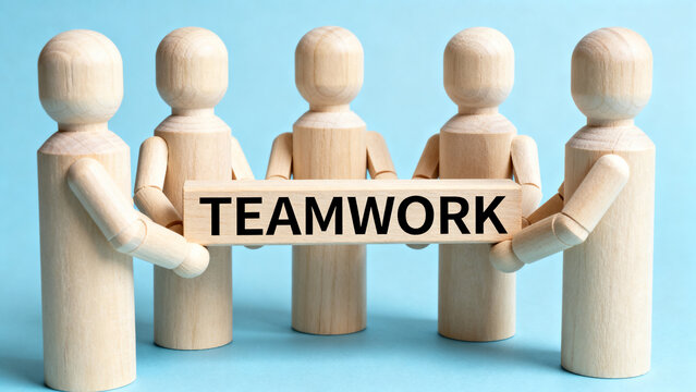 Teamwork concept with wooden figures holding sign together in unity