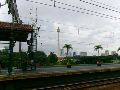 Monas monument and Jakarta skyline framed by station rooftop antennas