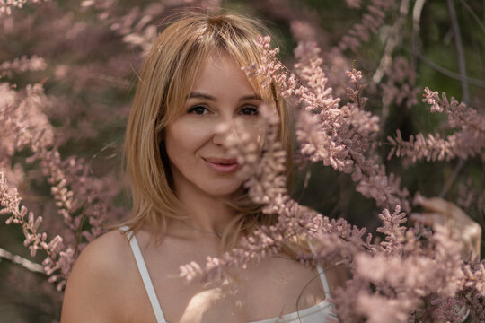 Woman tamarix flowers portrait smiling female model framed by pink spring blooms