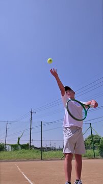 晴天のクレーコートで4kスローモーション撮影されたテニス選手の迫力あるサーブ前進フォーム