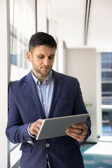 Focused adult businessman entrepreneur working on tablet in modern corporate workspace reviewing reports analyzing marketing data tracking tasks using digital tools for planning and decision making © fizkes