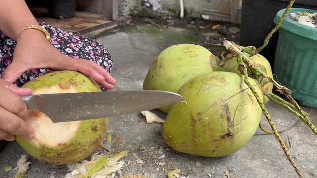 Woman Hand Chopping Top of Young Green Coconut with Big Knife
