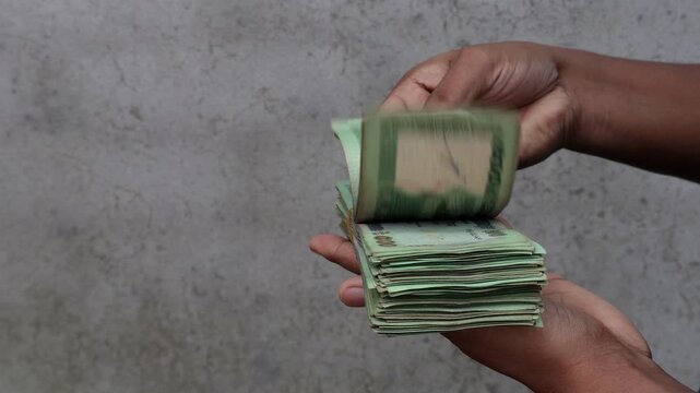 Close Up Shot of Hands Showing Thick Stack of 500 Taka Bangladeshi Currency Notes - Cash Payment, Business Profit, and Investment
