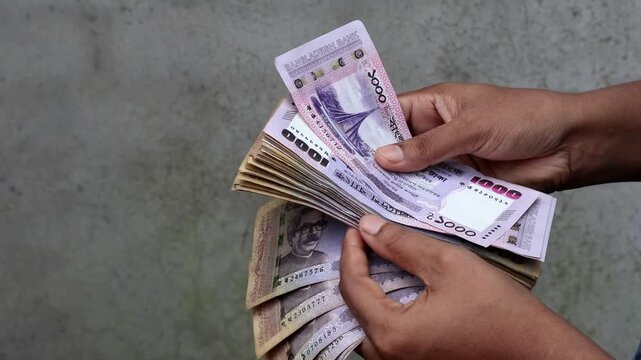 Hands Holding and Counting Stack of 1000 Bangladeshi Taka Notes - Wealth, Currency Exchange, Finance, and Business Concept