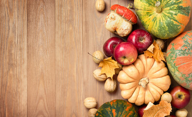 Fototapeta premium Autumn harvest with pumpkins, apples, and nuts on a wooden table, top view. Harvest celebration concept