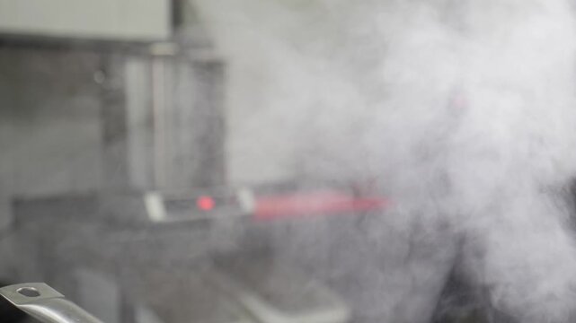 Dense white steam and smoke rising from pot on professional restaurant kitchen stove. Thick heavy vapor clouds, hot cooking process, dark blurred background, cinematic dense culinary atmosphere 4k