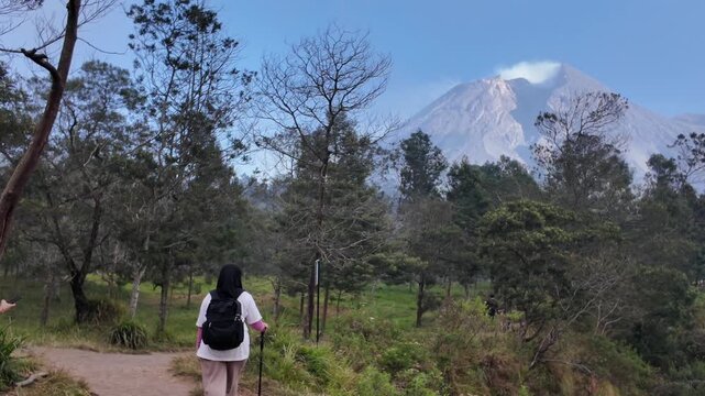 Young adventurous backpackers hiking on a mountain top above the clouds and volcano merapi backgrounds.