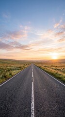 Obraz premium Open country road under a vibrant sunset sky with rolling hills and golden light
