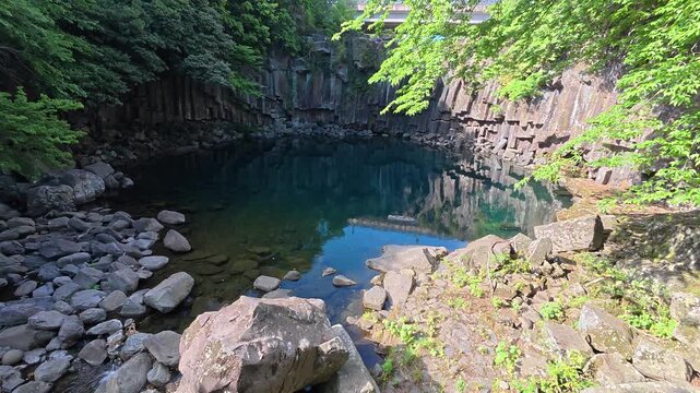 Rocky tide pool coastline near Cheonjeyeon Waterfalls, Jeju Island, South Korea.