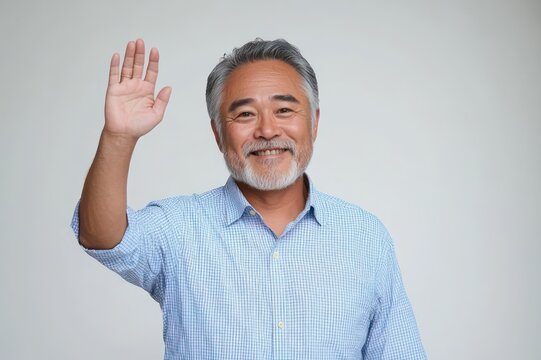 Middle-aged man with blurred face raising his hand in a friendly wave, wearing a light blue checked shirt against a plain light gray background
