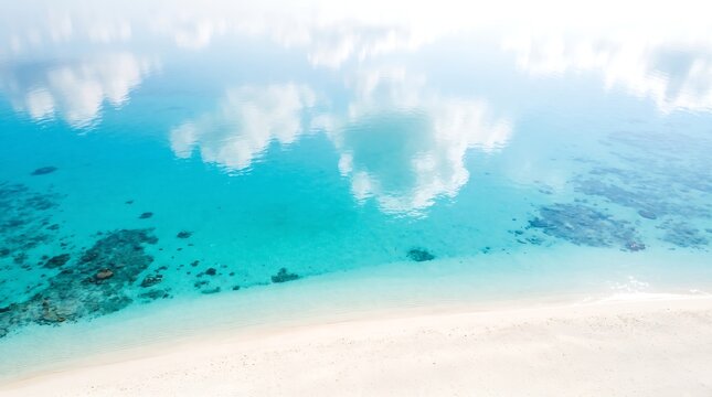 Turquoise ocean meeting white sand beach in bright sunlight