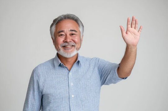 Middle-aged man with gray hair and blurred face wearing a blue checked button-up shirt waving in a friendly greeting against a plain light gray background