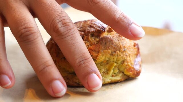 hand pick fresh baked scone on a wooden table at a cafe