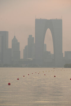Hazy Suzhou skyline with the Gate to the East over calm waterfront