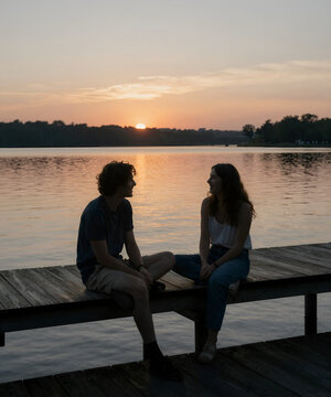 Two lifelong friends sitting on a wooden pier at sunset, sharing stories and laughter beside a calm lake, authentic friendship and emotional cinematic editorial photography