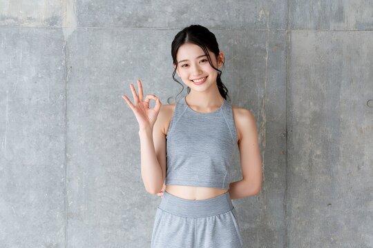 笑顔でOKサインする日本人女性ヘルシーなフィットネス姿