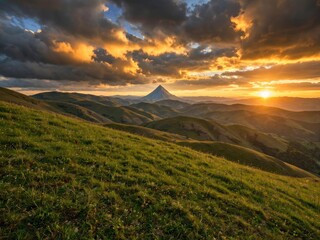Obraz premium Majestic Mountain Peak Bathed in Golden Sunset Light Over Rolling Hills.