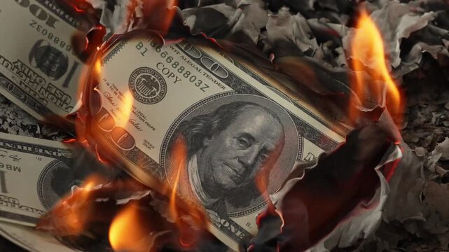 Burning prop 100‑dollar US banknotes with flames and ash debris