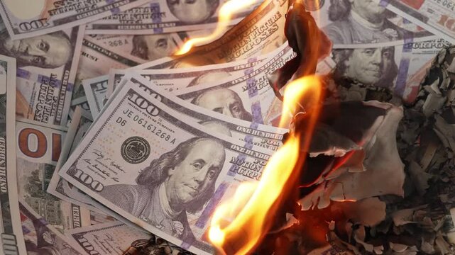 Burning prop 100‑dollar US banknotes with flames and ash debris