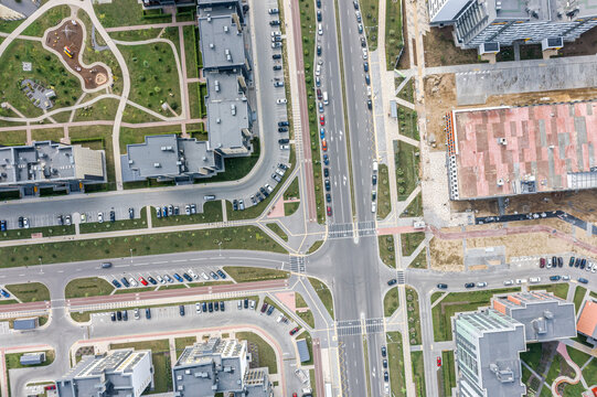 cityscape with street crossroad, residential houses and parking lots with parked cars. aerial overhead view.
