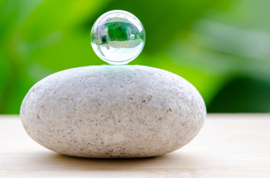 Closeup of crystal sphere on zen stone representing focus and mindful awareness, with customizable space for text.