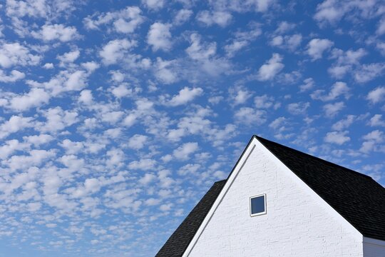 晴れた青空に映えるひつじ雲と新しい家の屋根と壁