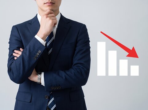 下降する業績グラフを前に真剣に思考するビジネスマン