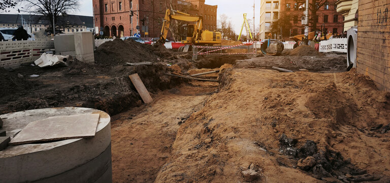 Big construction site. Excavated urban trench with manhole and paved surroundings