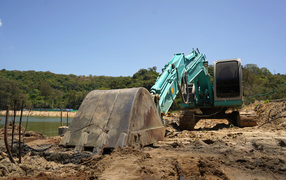 Building process city levee. Excavator dredging pond bank